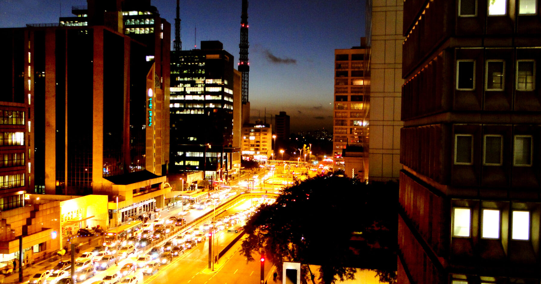Avenida Paulista in São Paulo at dusk with office towers and traffic lights