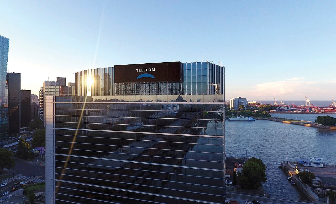 Glass tower with the Telecom logo at the top in Puerto Madero, Buenos Aires, with the port and the river behind it