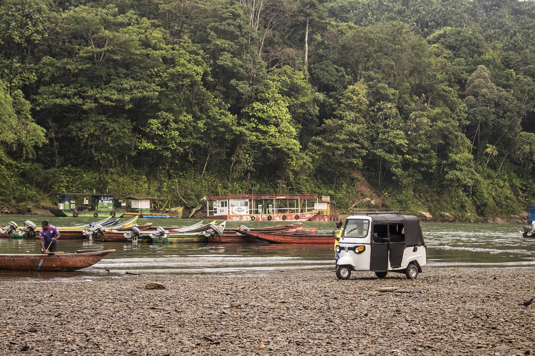 Boats and a three-wheeled taxi on the bank of the Telembí river with rainforest behind, Barbacoas, Nariño, Colombia