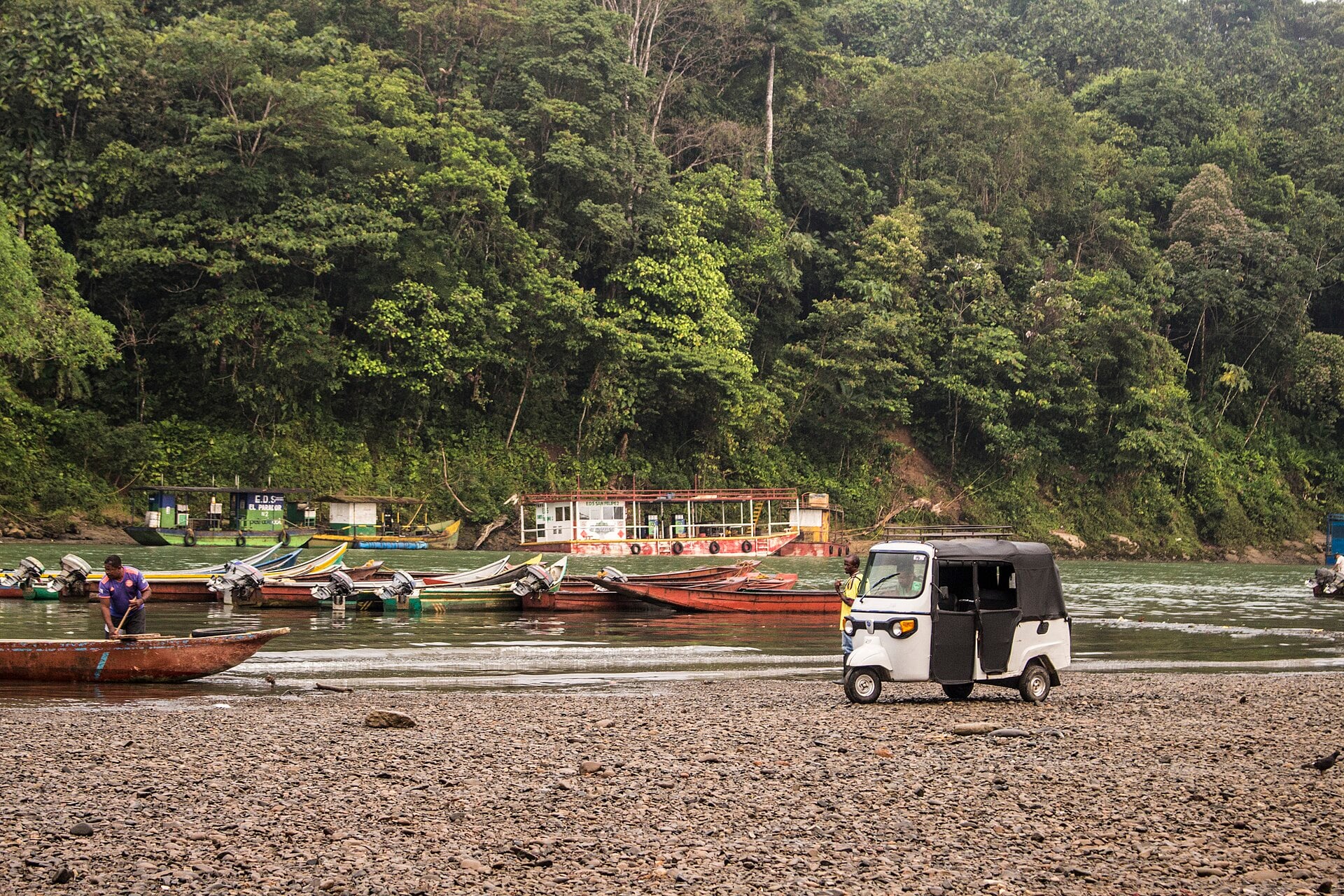 Boats and a three-wheeled taxi on the bank of the Telembí river with rainforest behind, Barbacoas, Nariño, Colombia