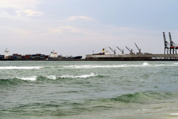 Container ship and port cranes along the quay at Lomé, Togo, seen from the beach