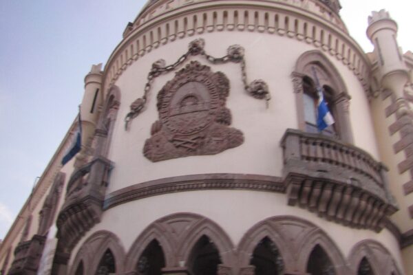 Curved facade of the former presidential palace in Tegucigalpa with the carved national coat of arms and Honduran flags