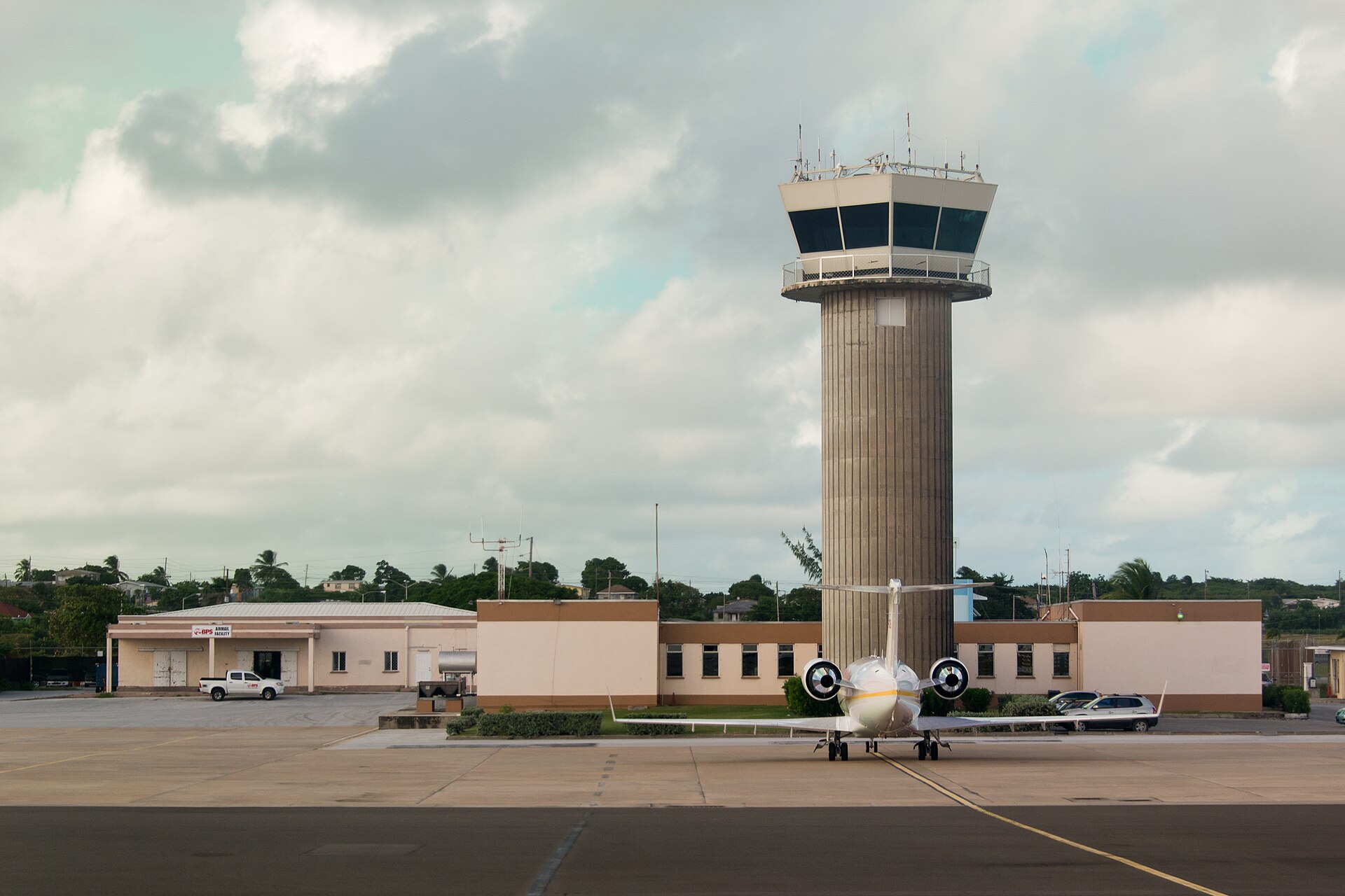 The control tower and terminal buildings of Grantley Adams International Airport with a small jet parked on the apron