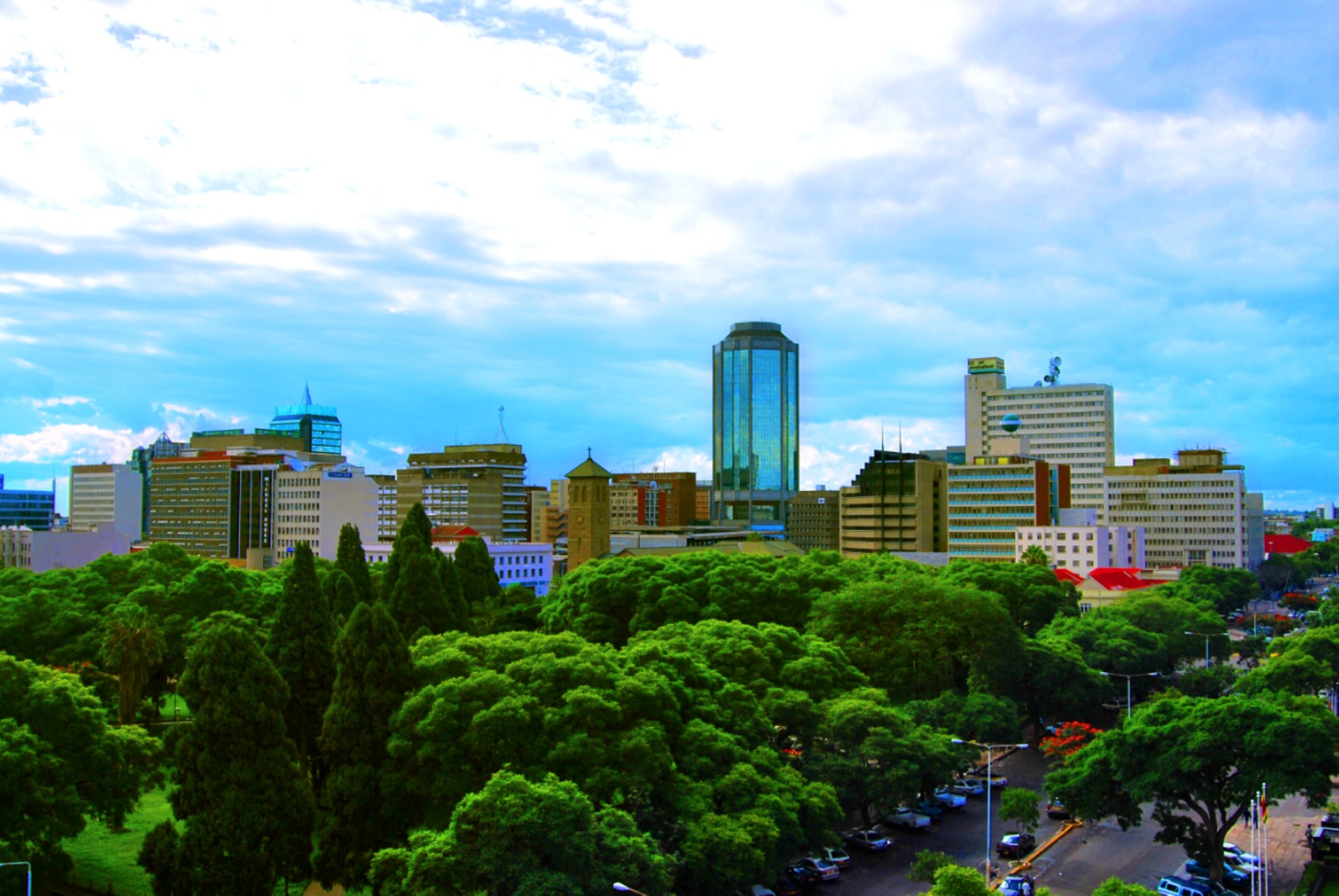 Harare city-centre office towers among green trees, with the glass tower of the Reserve Bank of Zimbabwe in the middle of the skyline