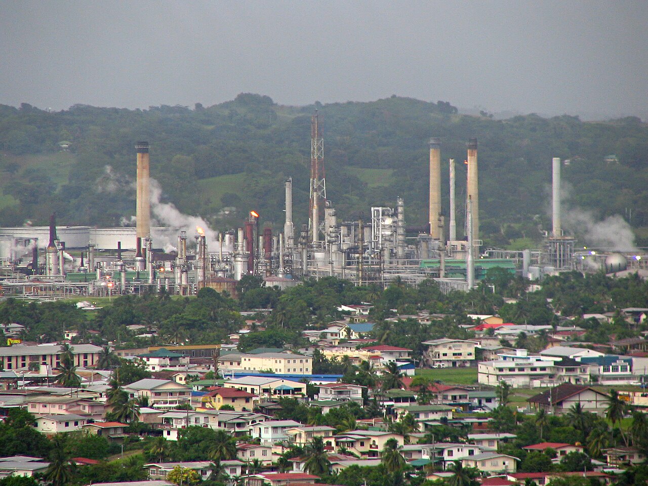 Chimneys and flares at the Pointe-a-Pierre oil refinery rising above houses in Trinidad