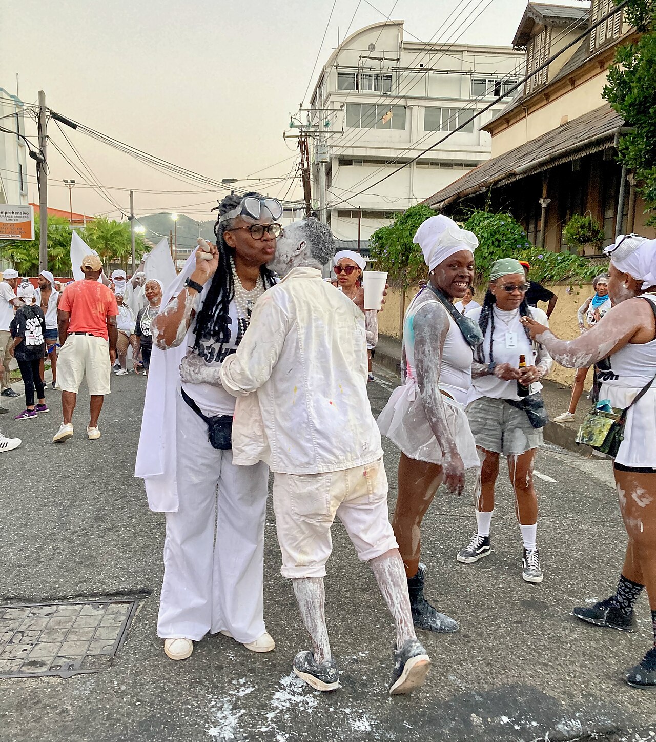 People in white clothes dusted with powder greet each other on a town street during jouvay, the pre-dawn start of Carnival in Trinidad