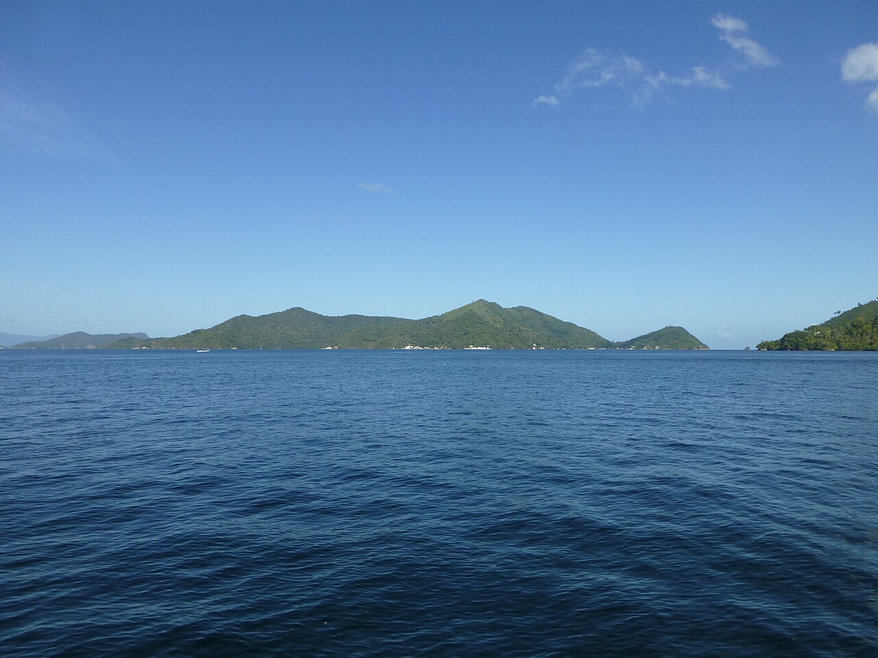 Green hills of Monos and Chacachacare islands rise from calm blue water off Chaguaramas, Trinidad