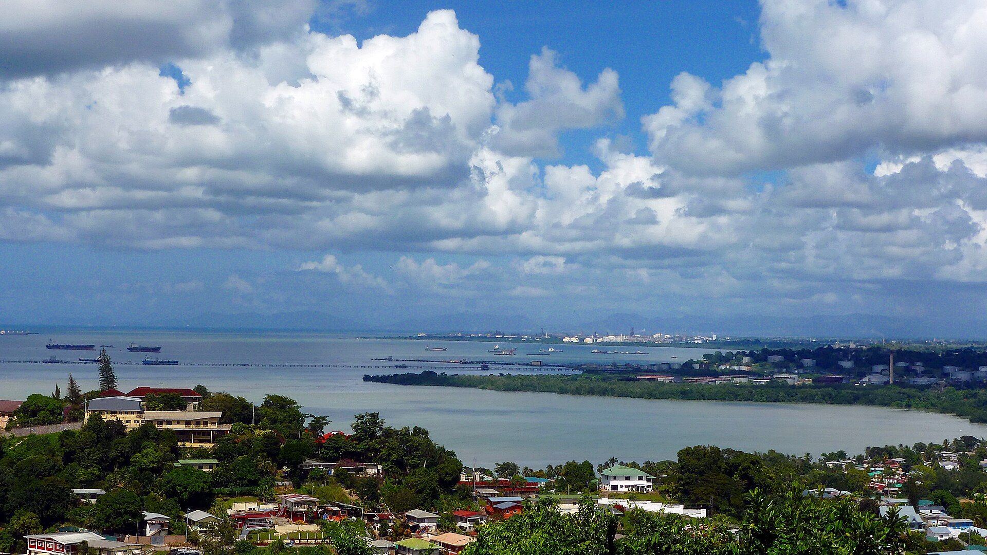 Gulf of Paria coast at Pointe-a-Pierre, Trinidad, with refinery storage tanks and jetties along the industrial shoreline