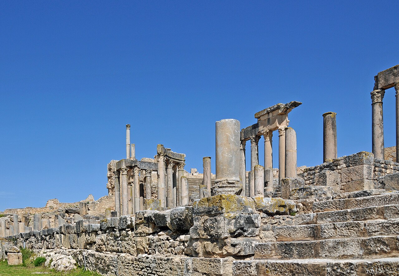 Roman columns and a stone stairway at the ancient site of Dougga in northern Tunisia under a deep blue sky