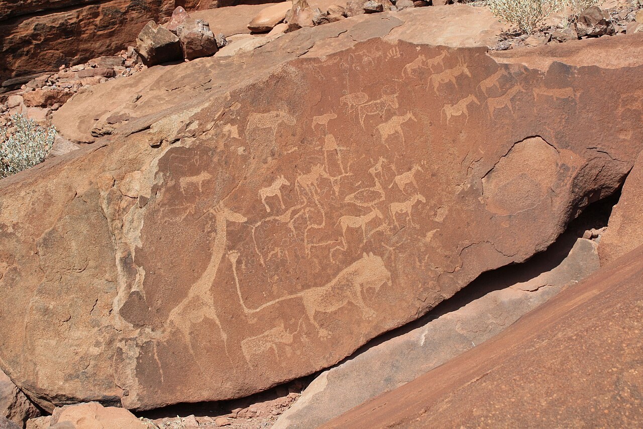 Rock engraving of giraffes, a lion and other animals on a red sandstone slab at Twyfelfontein, Namibia