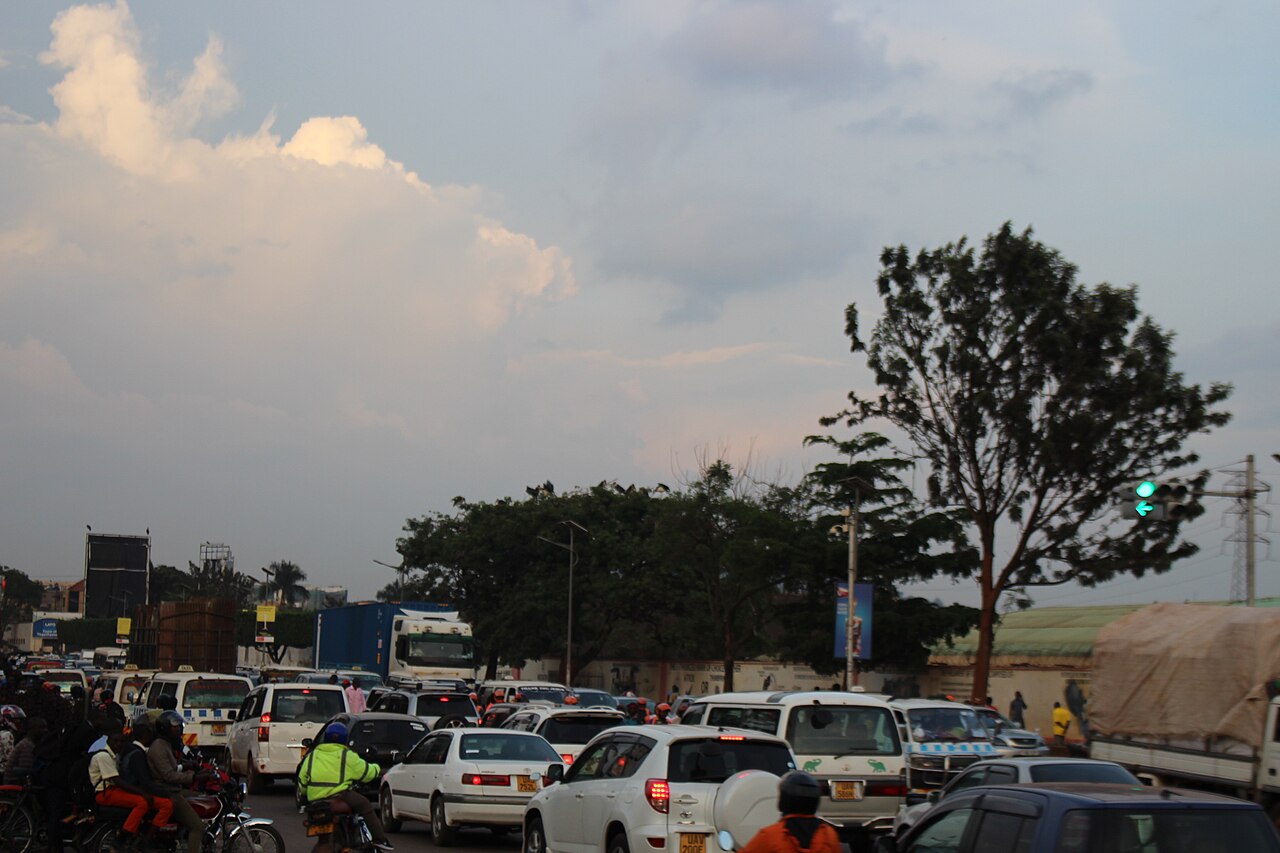 Evening traffic of cars, minibuses and motorcycle taxis on a road in Kampala, Uganda, under a cloudy sky