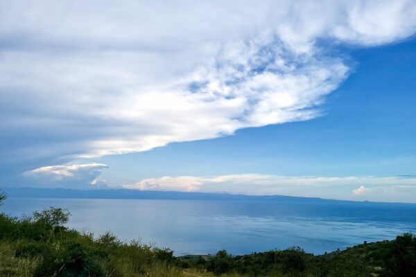 Lake Albert seen from a hillside in Hoima district, western Uganda, with blue water and a long cloud overhead