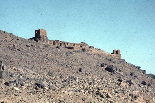 A ruined mud-brick fortress on a rocky hillside above the town of Tessalit in northern Mali under a clear sky