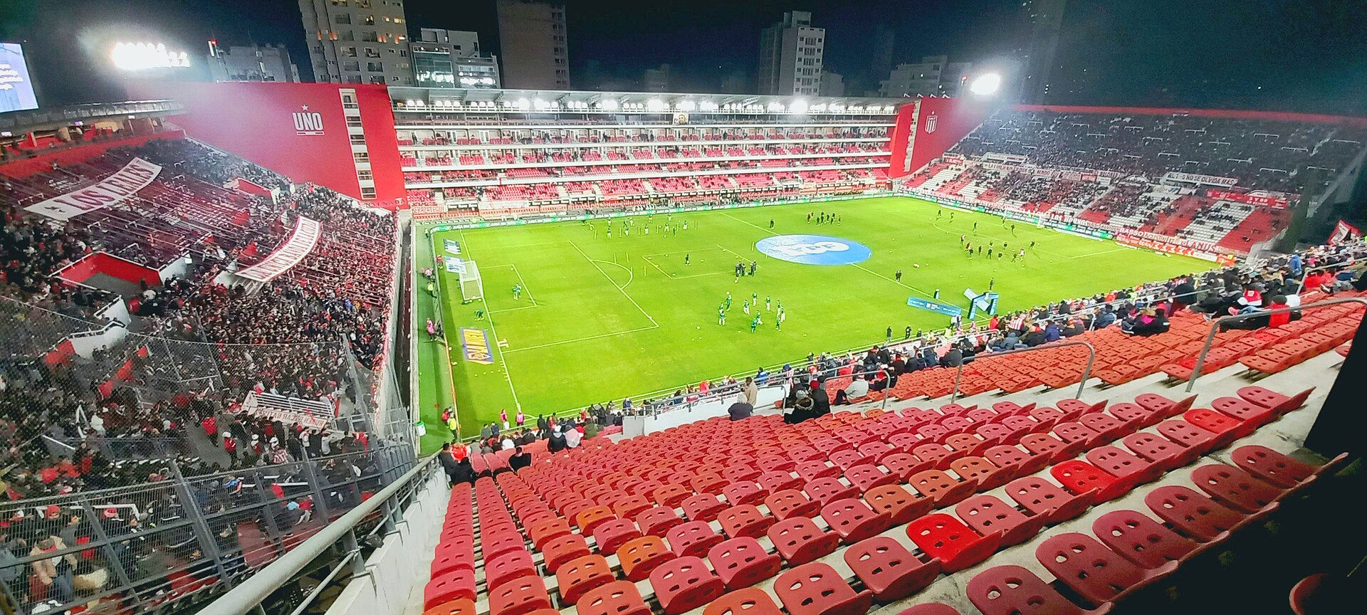 The red stands and floodlit pitch of the Estadio UNO Jorge Luis Hirschi in La Plata before an Estudiantes home match at night