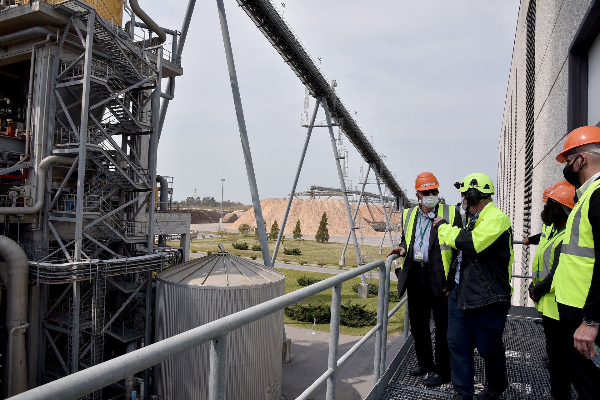 Visitors in hard hats and safety vests on a walkway at the UPM pulp mill near Fray Bentos