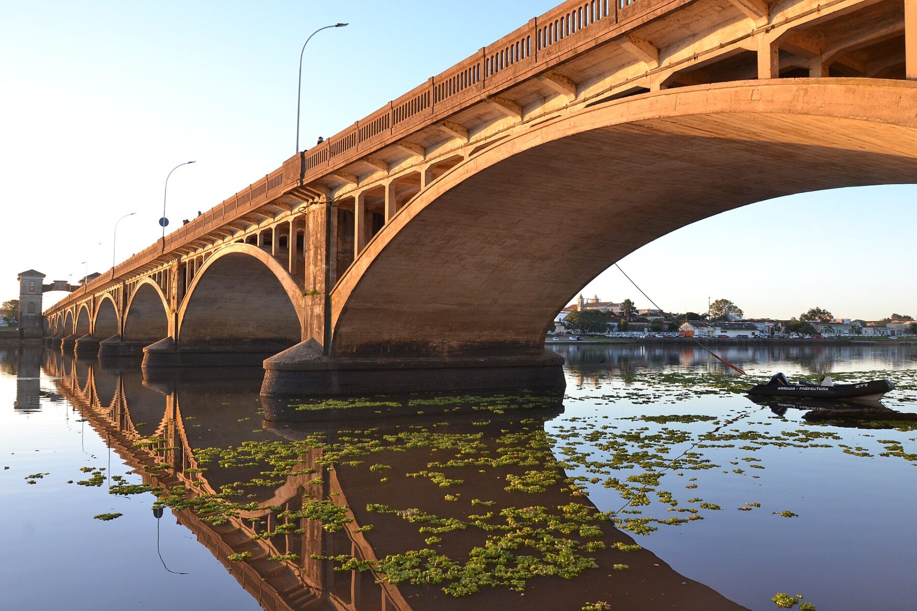 Concrete arched bridge over a river at sunrise with reflections, the Barão de Mauá International Bridge between Río Branco in Uruguay and Jaguarão in Brazil