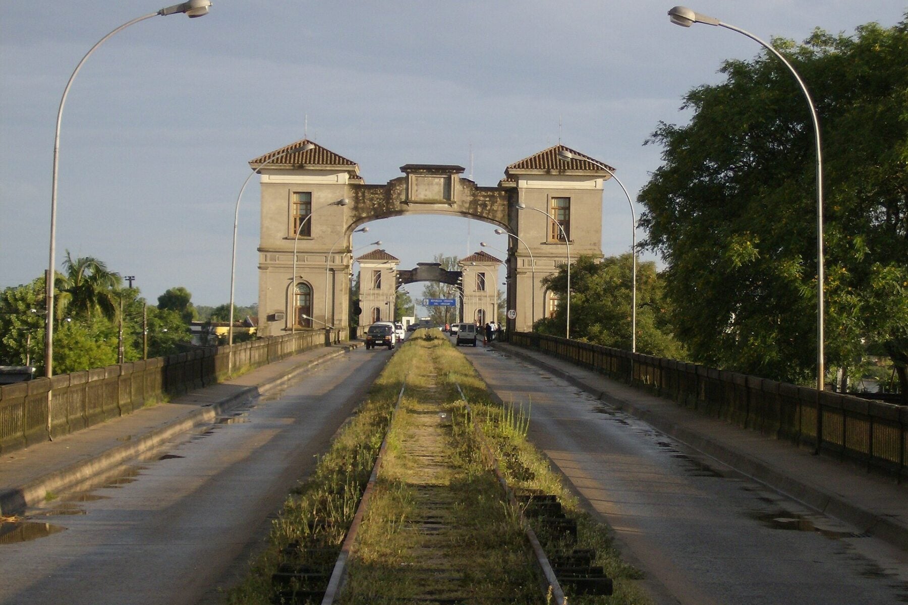 Road deck of an international bridge with twin stone gate towers and a sign reading Republica Oriental del Uruguay, seen from the Brazilian side at Jaguarão