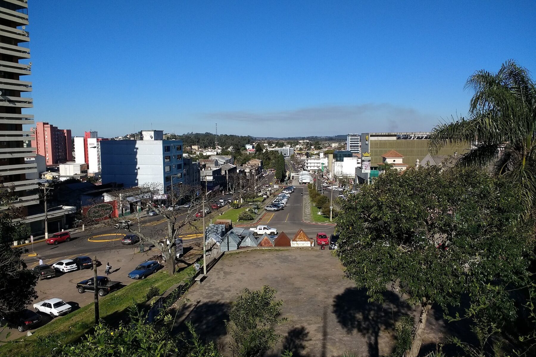 View over the border area between Rivera in Uruguay and Santana do Livramento in Brazil, with a wide avenue, low buildings and trees under a blue sky