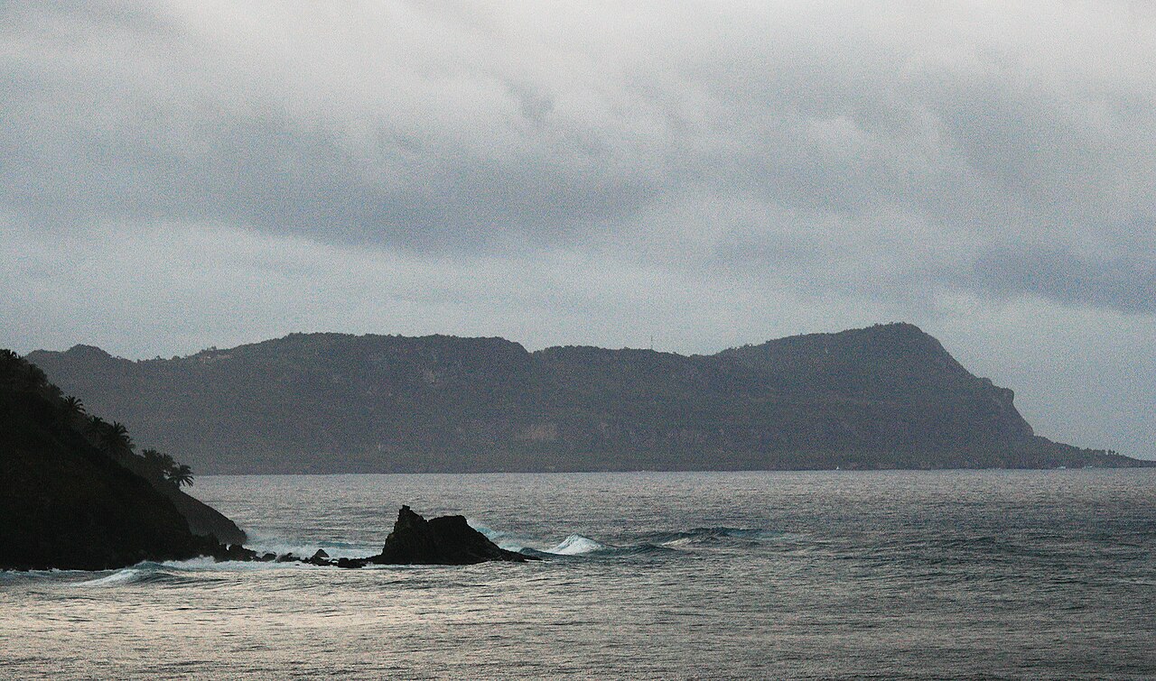The dark headland of Cabo Cabrón on the Samaná Peninsula rising above a grey Atlantic sea under heavy clouds