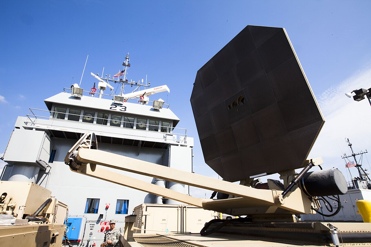 The black octagonal antenna panel of the Active Denial System on a dock in front of a US Army vessel