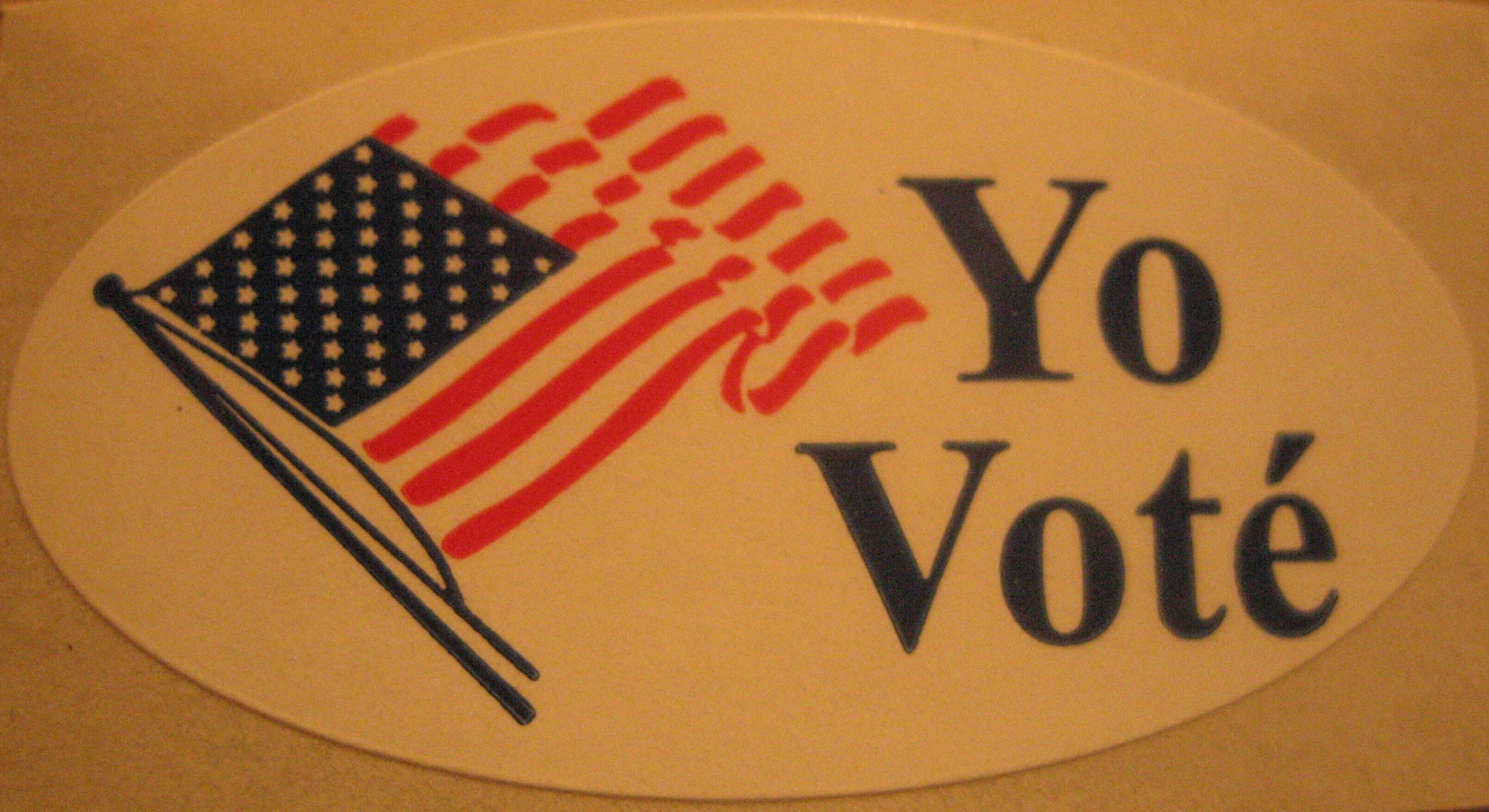 An oval Yo Voté sticker with a waving US flag