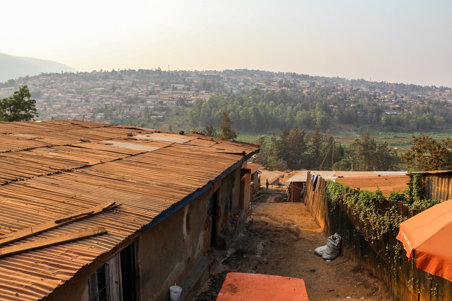 Hillside neighbourhoods of Kigali, Rwanda, with corrugated metal roofs in the foreground and a hazy ridge beyond