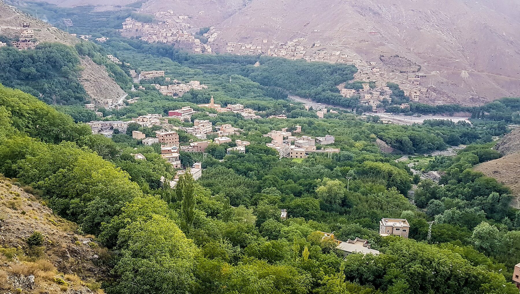 Green valley of Imlil in the High Atlas with clusters of village houses on brown mountain slopes
