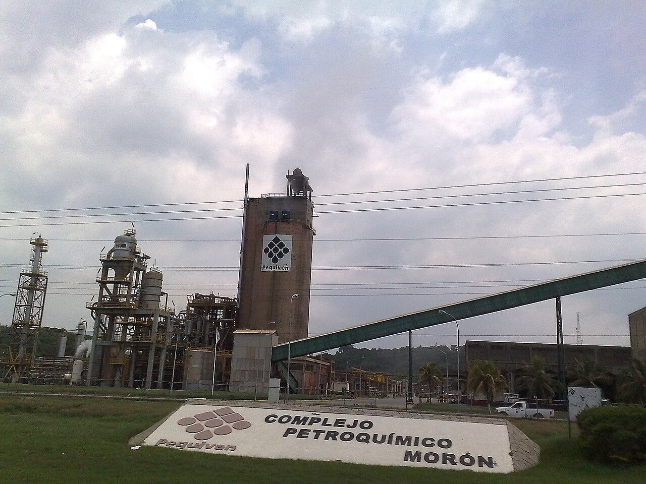 Pequiven sign and industrial towers at the Morón Petrochemical Complex in Venezuela under a cloudy sky