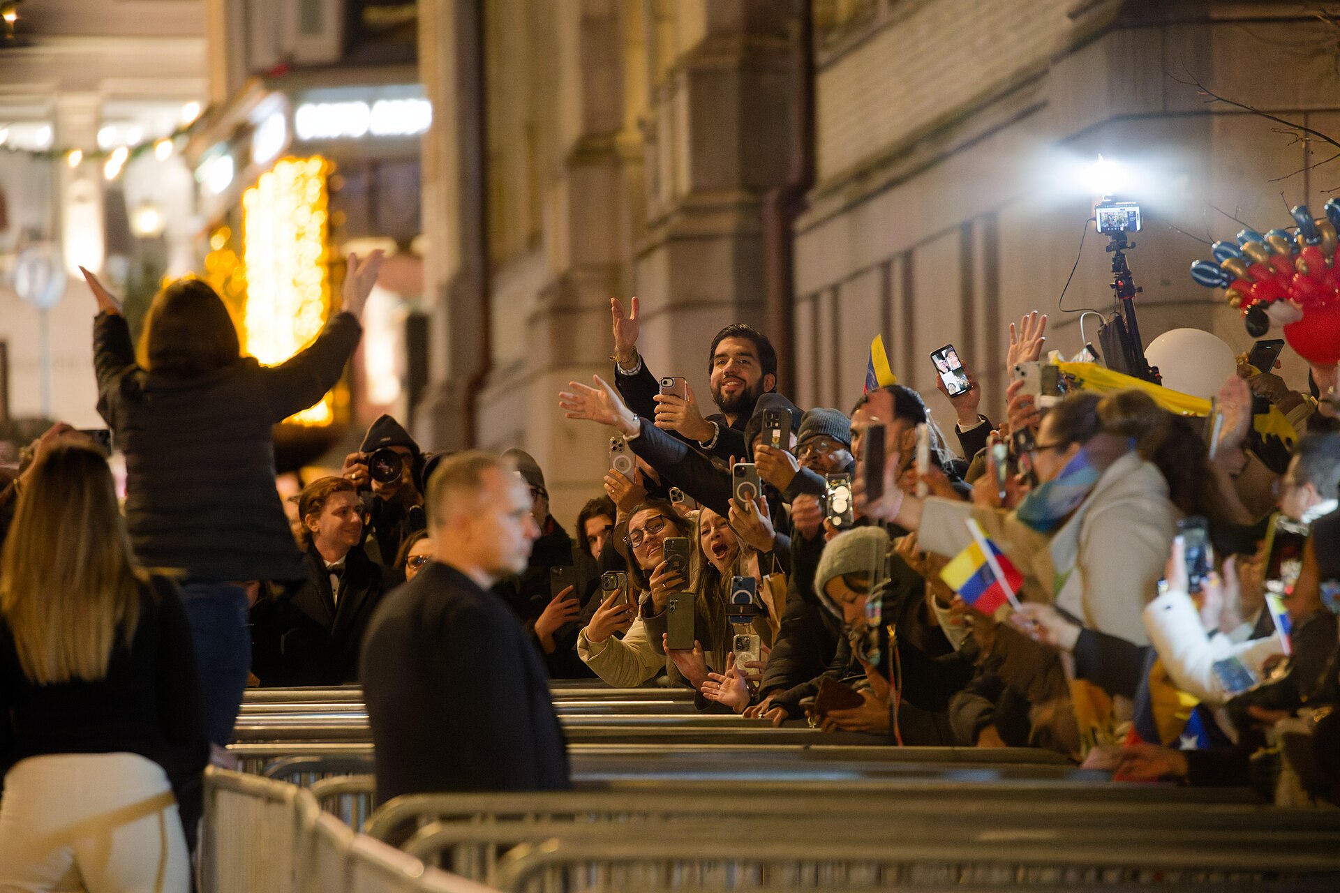 María Corina Machado, seen from behind, waves to a crowd of supporters with Venezuelan flags in Oslo