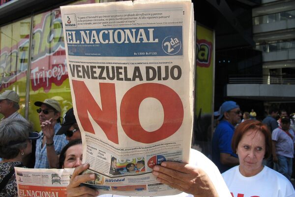 A man holds up the front page of El Nacional newspaper, with the headline 'Venezuela dijo NO' in large red letters, in front of a crowd.
