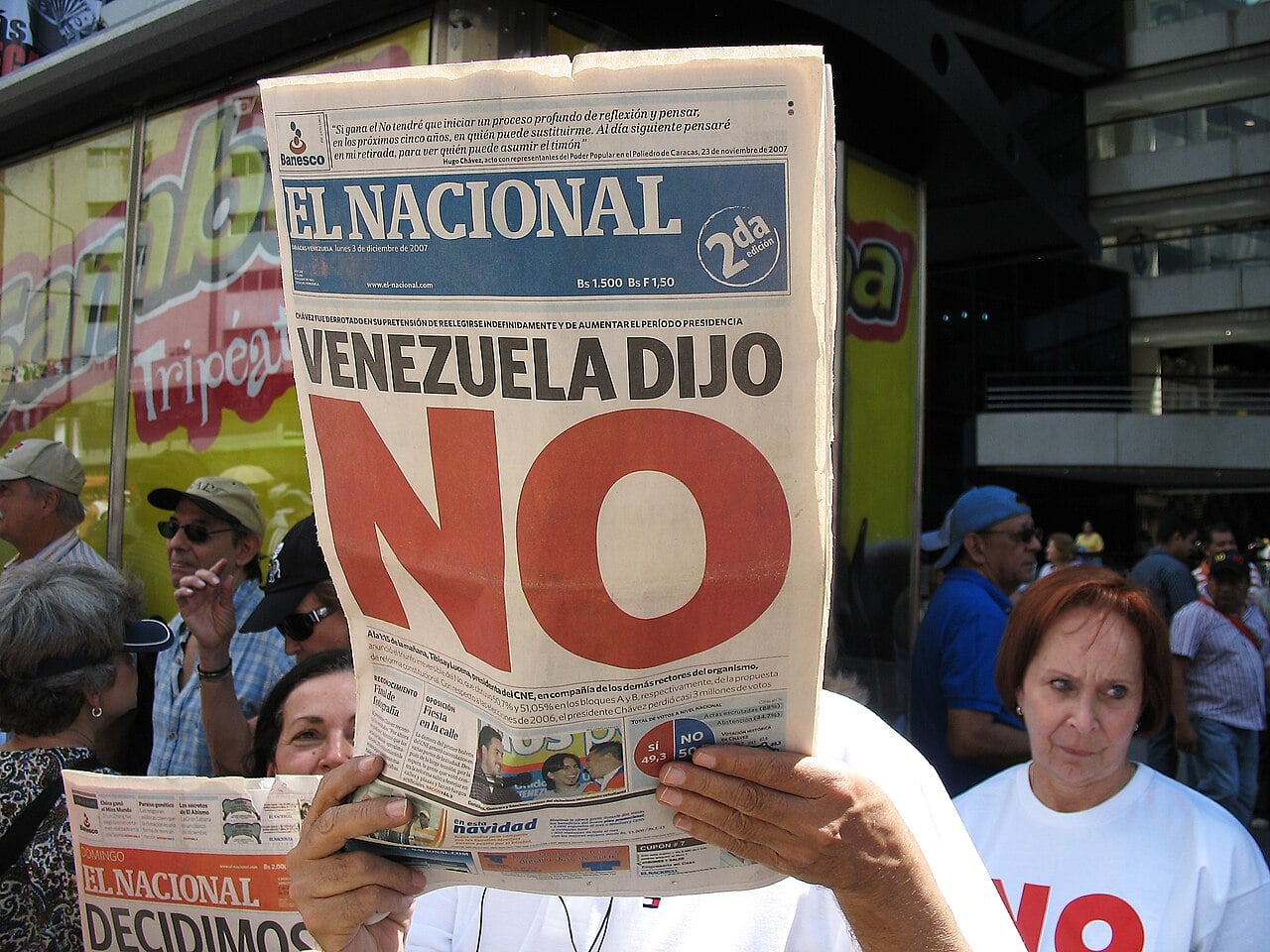 A man holds up the front page of El Nacional newspaper, with the headline 'Venezuela dijo NO' in large red letters, in front of a crowd.