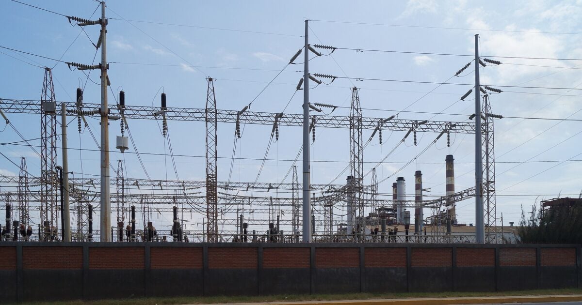 High-voltage power lines and a substation in Maracaibo, Venezuela, with the chimneys of a power plant in the background