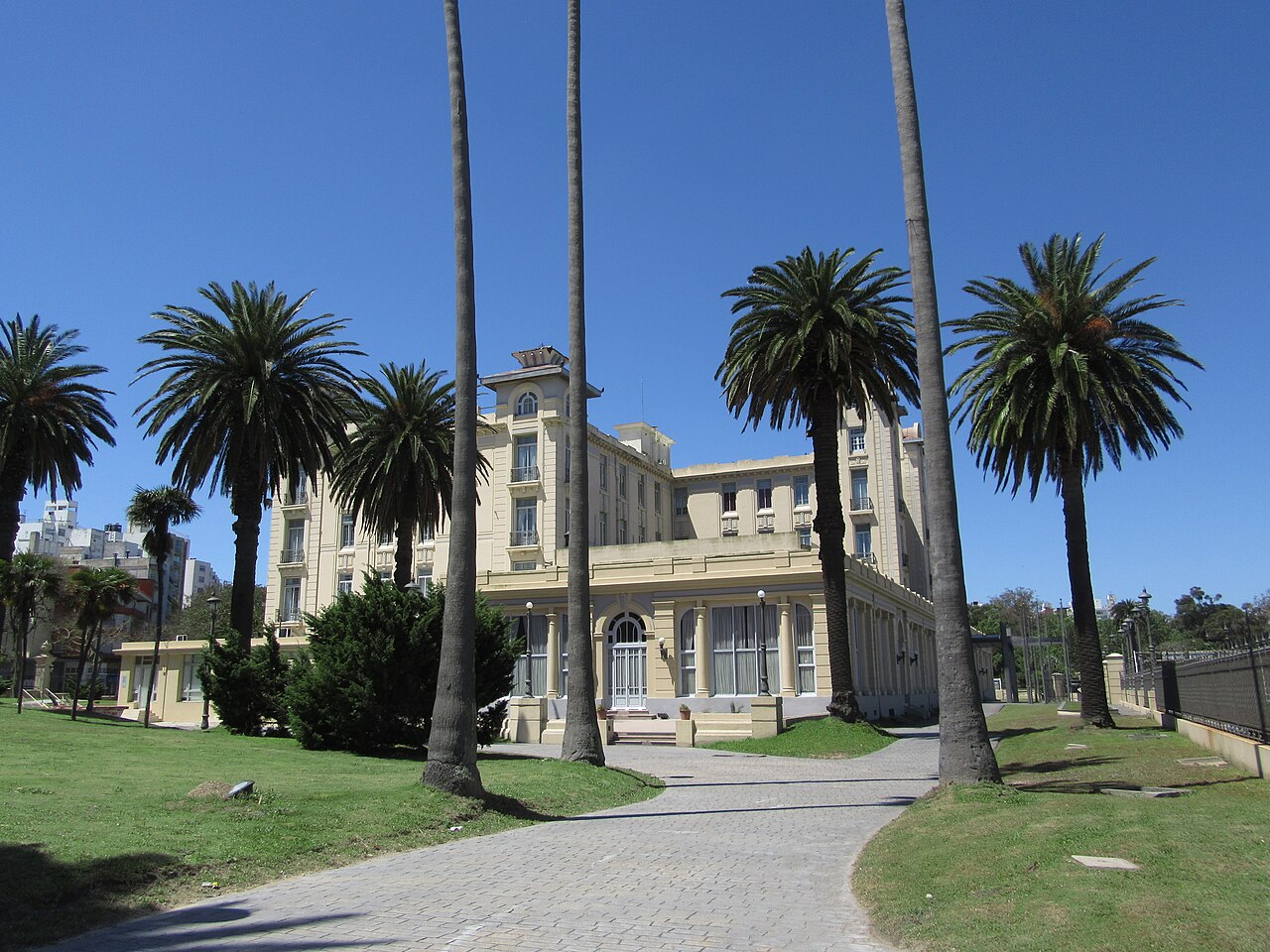 Palm-lined path leading to the cream-coloured Edificio Mercosur, a former hotel, in Montevideo under a clear sky