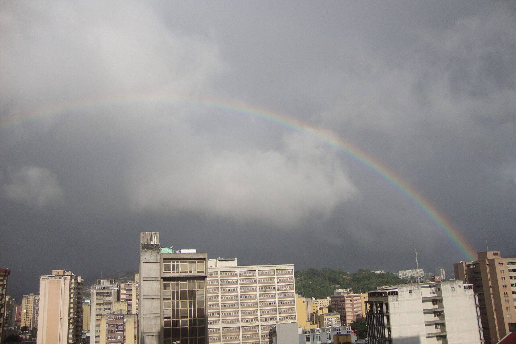 Rainbow over downtown Caracas, Venezuela, with office and apartment blocks under storm clouds
