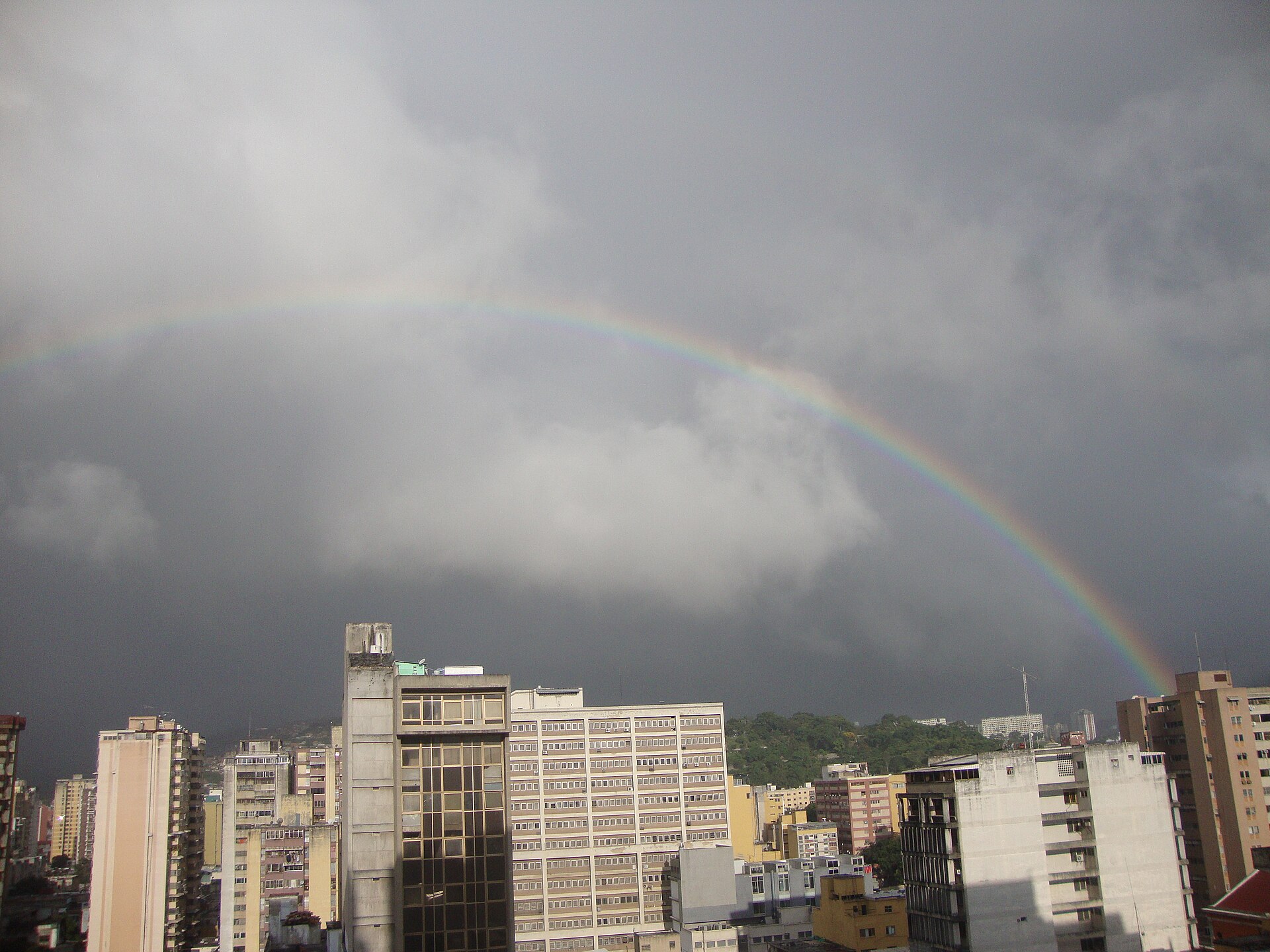 Rainbow over downtown Caracas, Venezuela, with office and apartment blocks under storm clouds