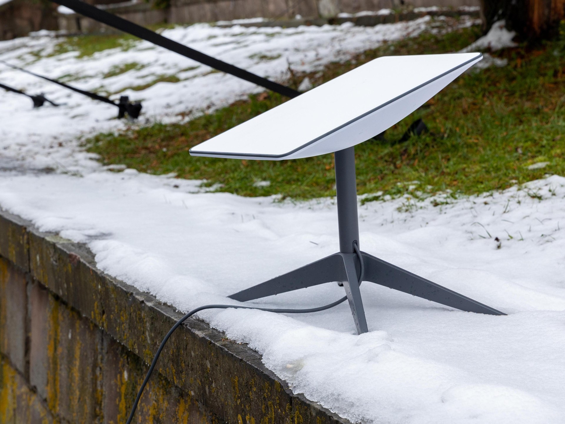 A Starlink satellite internet terminal standing on a snow-covered wall