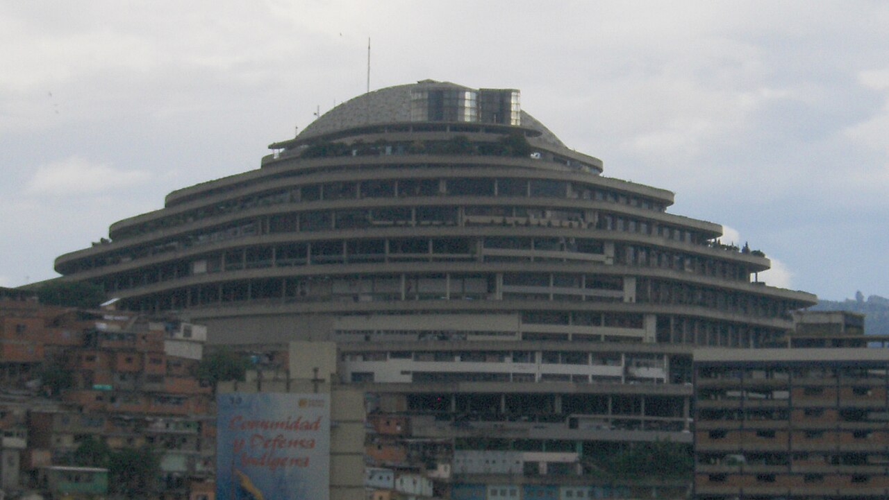 The tiered, dome-topped El Helicoide building rising above hillside housing in Caracas under a grey sky