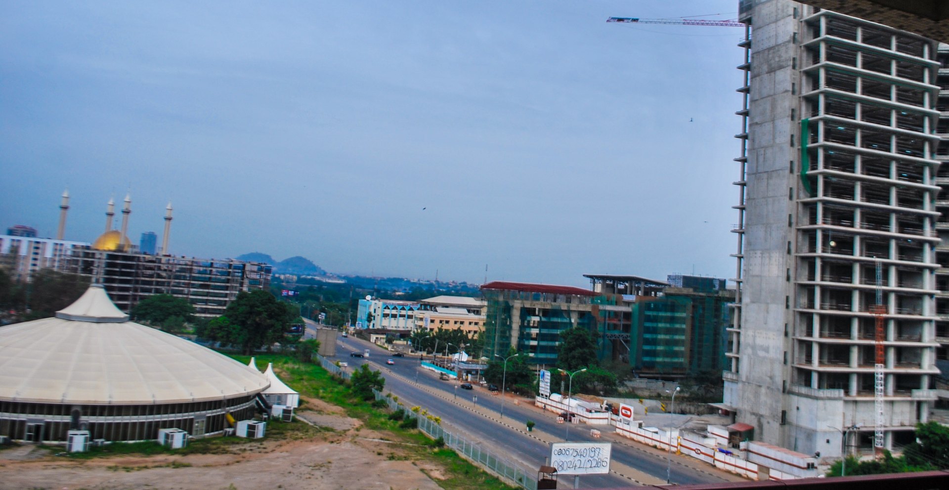 Abuja skyline with the golden dome and minarets of the National Mosque on the left and a high-rise under construction on the right