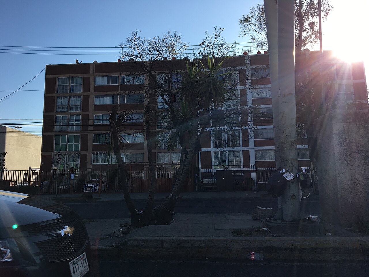 Five-storey brick and white apartment block seen from a street in Mexico City