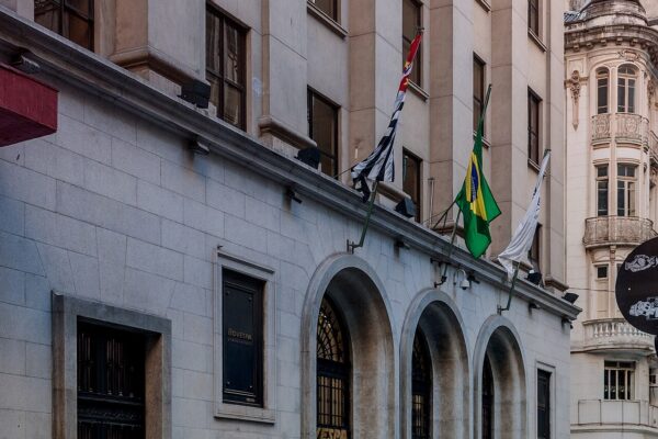 Entrance of the B3 stock exchange building in central São Paulo with the Brazilian and São Paulo state flags above its arched doors