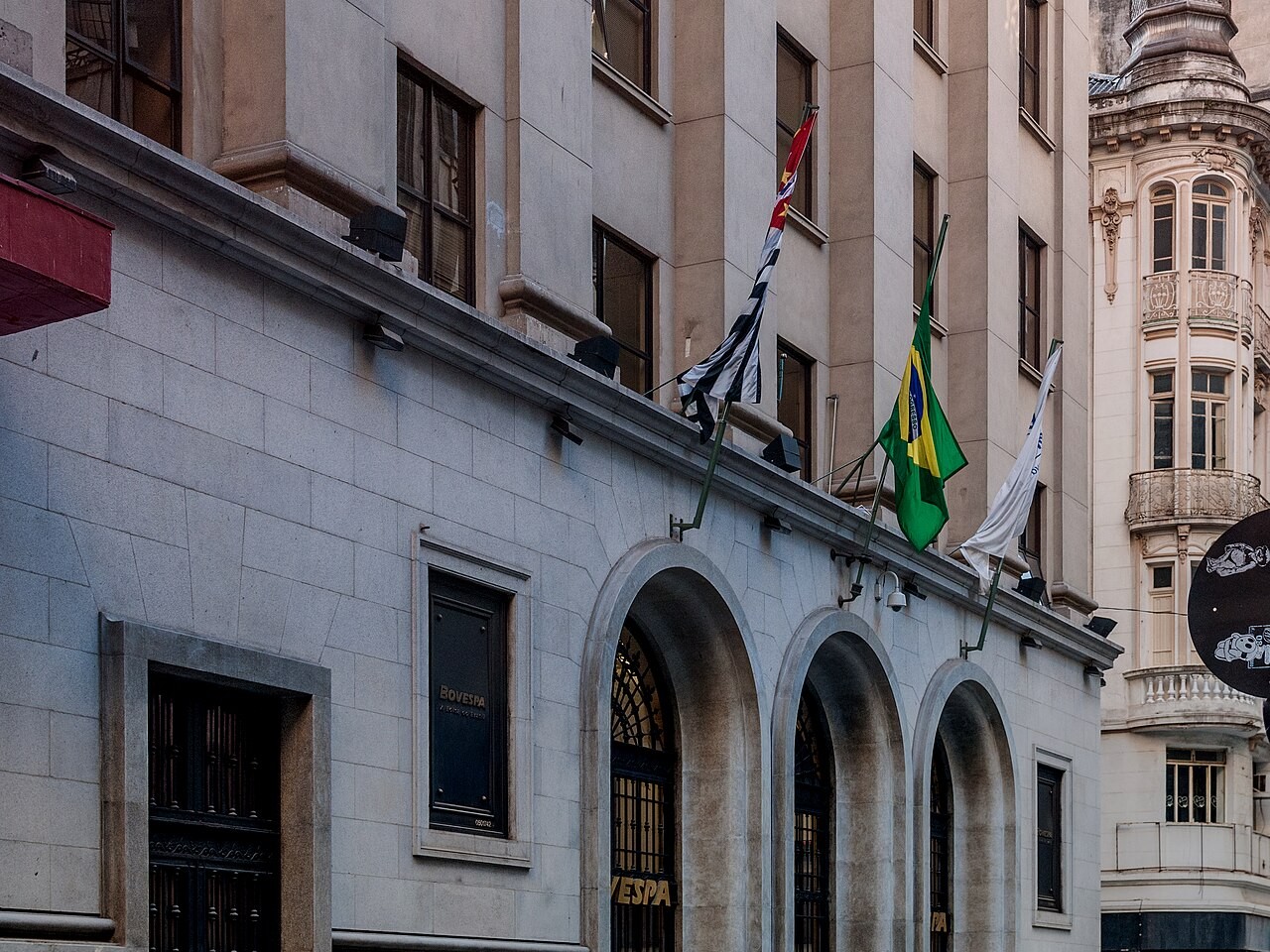 Entrance of the B3 stock exchange building in central São Paulo with the Brazilian and São Paulo state flags above its arched doors