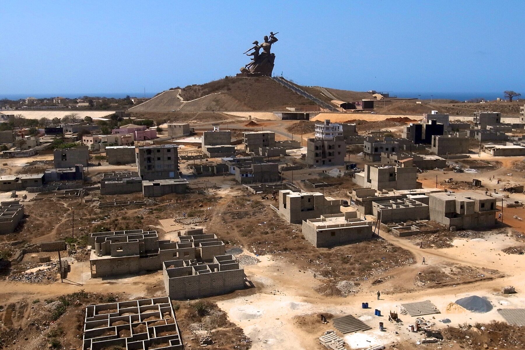 The African Renaissance Monument on a hill above Dakar, Senegal, under a clear blue sky with the Atlantic behind