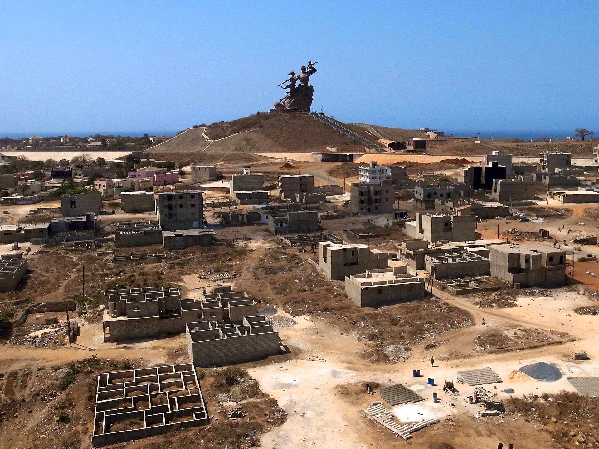 The African Renaissance Monument on a hill above Dakar, Senegal, under a clear blue sky with the Atlantic behind