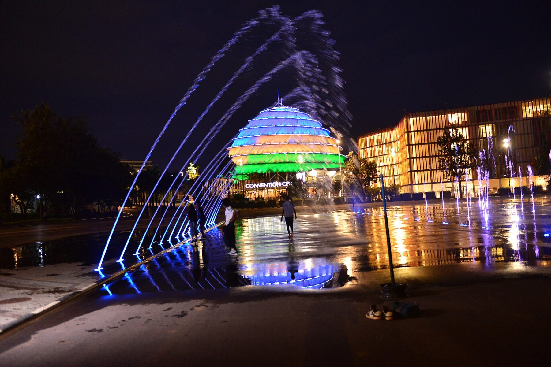 The Kigali Convention Centre dome lit up at night behind the fountains of its square in Kigali, Rwanda