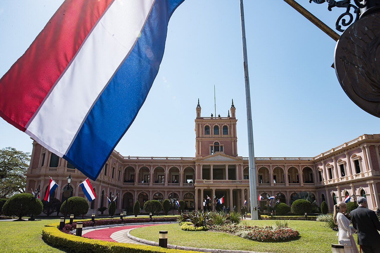 The pink Palacio de López in Asunción with gardens in front and a large Paraguayan flag in the foreground
