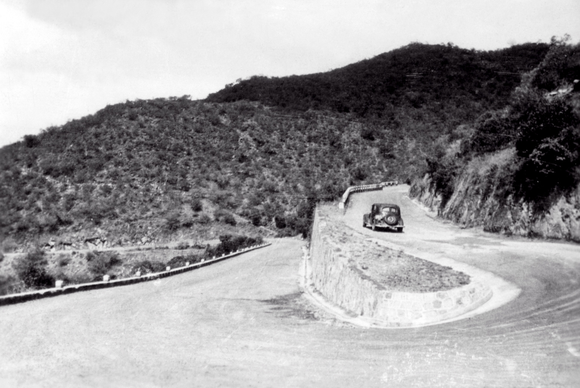 Black-and-white photo of a car on a hairpin bend on the Asmara to Massawa road, late 1940s
