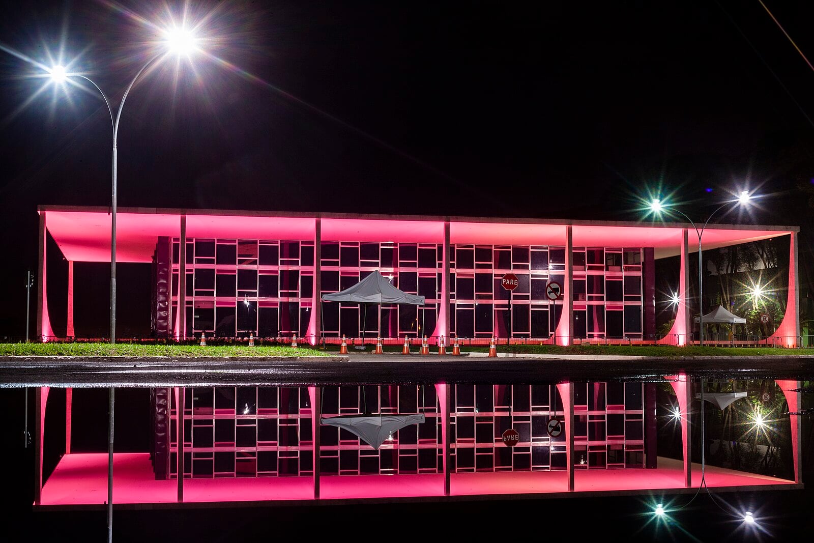 The Supreme Federal Court building in Brasília lit in pink at night, with its reflection in a pool of water