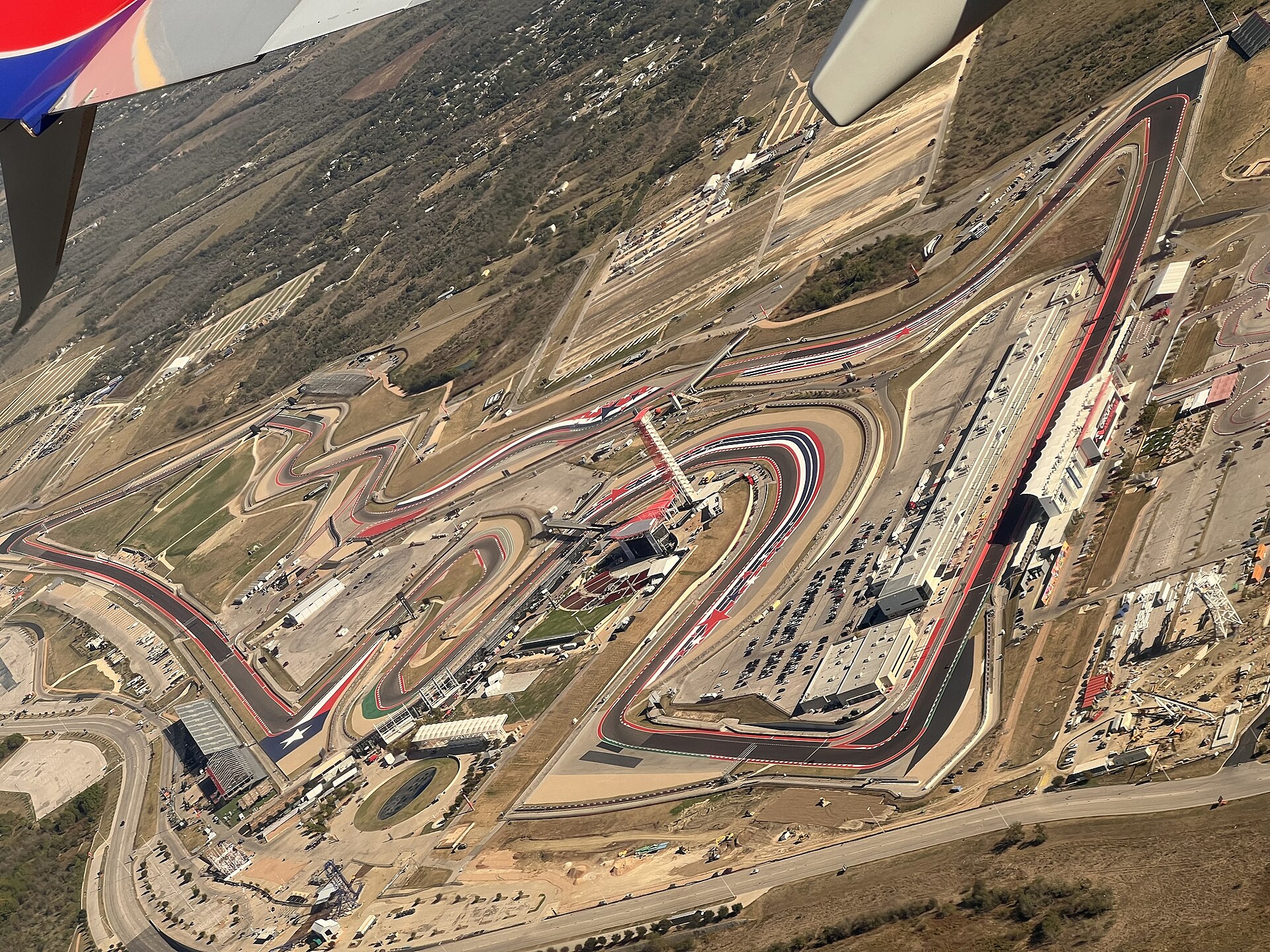 Aerial view of the winding Circuit of the Americas track and its paddock buildings, seen from an airliner window near Austin, Texas
