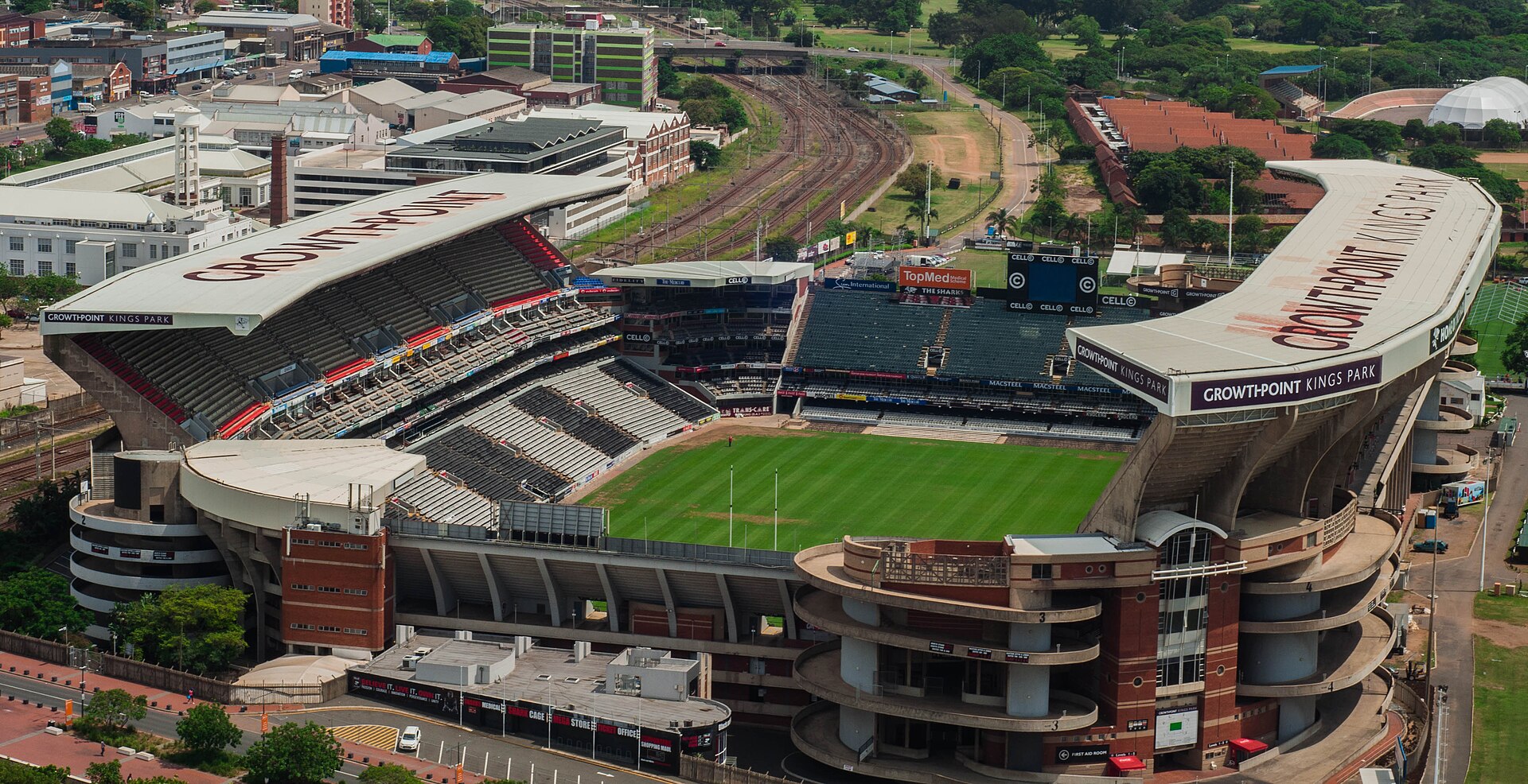 Aerial view of the Kings Park stadium in Durban with its curved roof, green pitch and railway line behind