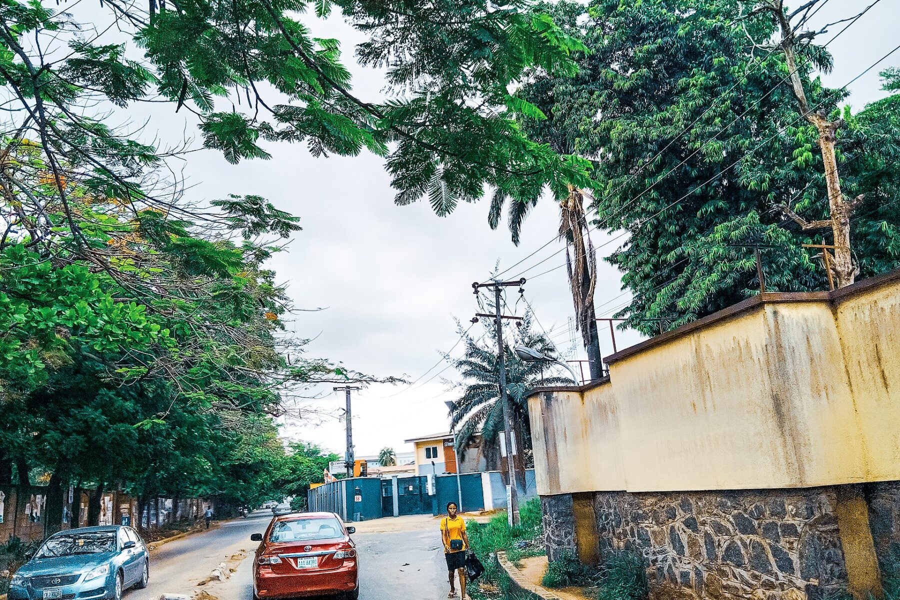 Tree-lined street in Ikeja GRA, Lagos, with parked cars.